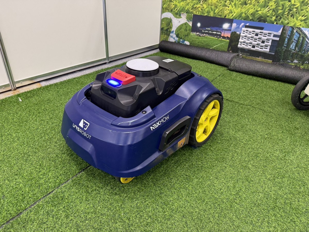 人工芝の上に展示された紺色と黄色のURSROBOT NEXMOW